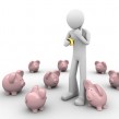 man making choice where to put savings holds coin in hands in the crowd of piggybanks man making choice where to put savings holds coin in hands in the crowd of piggybanks